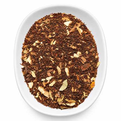 A top-down view of loose-leaf tea in a white oval dish against a white background. The tea consists of dark brown rooibos tea pieces with scattered light beige citrus peel flakes.