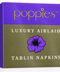 A square product box for Poppies Luxury Airlaid Tablin Napkins, featuring a purple top section with gold lettering and a muted olive-green lower section with a purple flower graphic and white text.