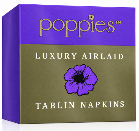 A square product box for Poppies Luxury Airlaid Tablin Napkins, featuring a purple top section with gold lettering and a muted olive-green lower section with a purple flower graphic and white text.