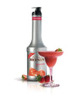 Monin strawberry syrup bottle with a strawberry-themed glass on a white background
