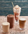 Three coffee drinks with whipped cream and a straw on a textured surface, featuring the Sweetbird brand.