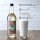 Sweetbird coconut syrup bottle with a glass of whipped cream and a straw on a wooden surface.