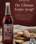 Bottle of Sweetbird Mince Pie Syrup with mince pies on a wooden board against a brown background.