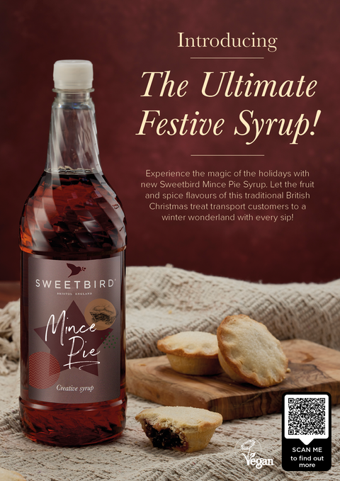 Bottle of Sweetbird Mince Pie Syrup with mince pies on a wooden board against a brown background.