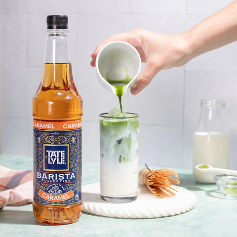 Tate & Lyle Barista Collection Caramel syrup being poured into a glass with ice and green liquid.