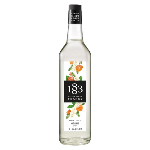 A bottle of 183 Maison Matrio France Gomme Cane syrup, featuring a clear glass bottle with a white and black label decorated with orange and green floral illustrations, set against a plain white background.