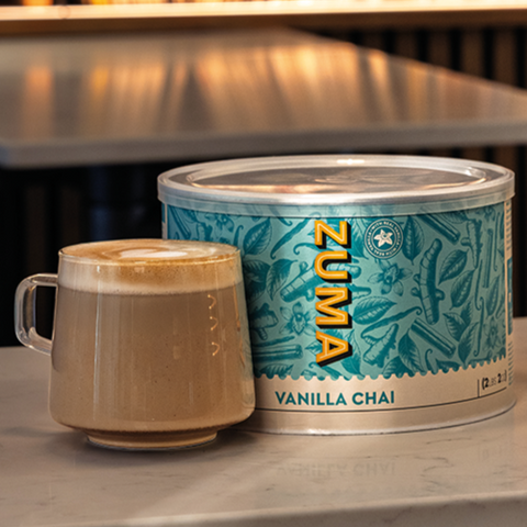Zuma Vanilla Chai canister with a cup of coffee on a table in a cozy setting.